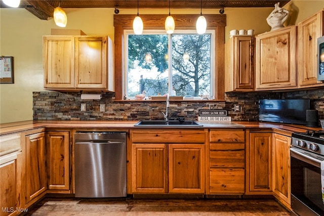 kitchen featuring appliances with stainless steel finishes, decorative backsplash, sink, and decorative light fixtures