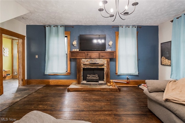 living room featuring an inviting chandelier, dark wood-type flooring, a textured ceiling, and a fireplace