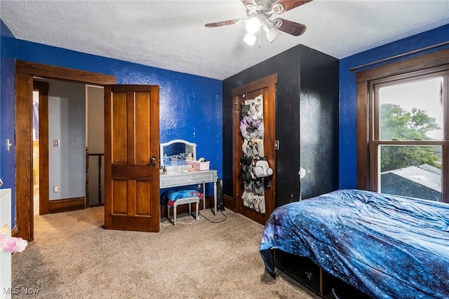 carpeted bedroom with ceiling fan and a textured ceiling