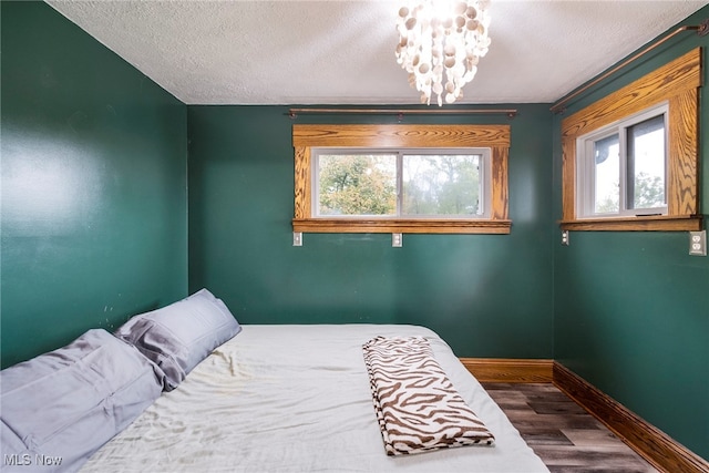 bedroom featuring a textured ceiling, wood-type flooring, and a notable chandelier