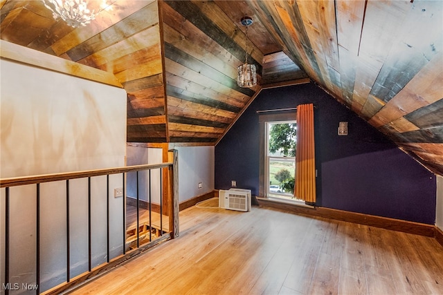 additional living space with wood ceiling, a chandelier, lofted ceiling, light hardwood / wood-style flooring, and a wall mounted AC