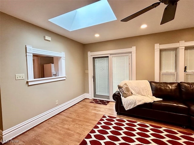 living room with a skylight, ceiling fan, light hardwood / wood-style floors, and baseboard heating