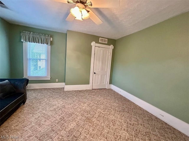 interior space with ceiling fan, carpet, and a textured ceiling