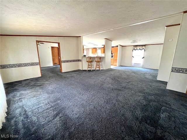 carpeted empty room with a textured ceiling, crown molding, and vaulted ceiling