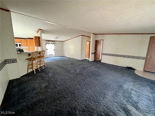 unfurnished living room with dark carpet, a textured ceiling, and crown molding