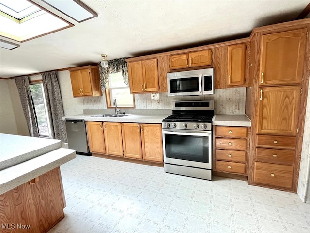 kitchen with a skylight, appliances with stainless steel finishes, plenty of natural light, and sink