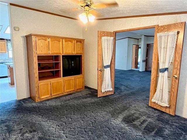 unfurnished living room with a textured ceiling, crown molding, ceiling fan, and dark carpet