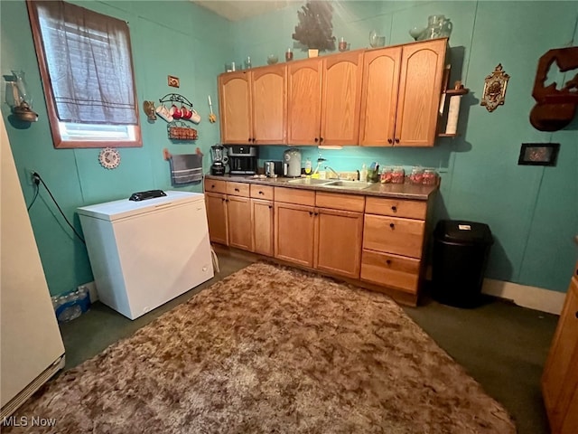 kitchen featuring refrigerator, light brown cabinets, dark colored carpet, and sink