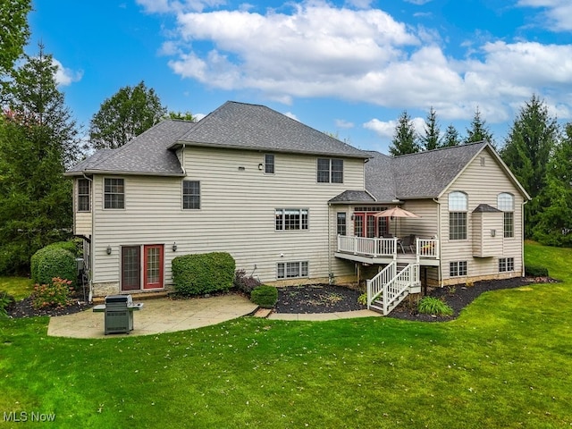 rear view of property featuring a patio, a deck, and a yard