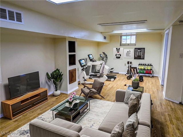 living area featuring baseboards, visible vents, and wood finished floors