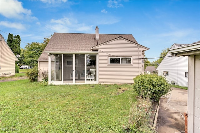 rear view of property featuring a lawn and a sunroom