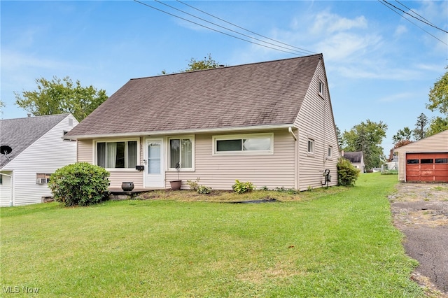 view of front of property featuring a garage, a front lawn, and an outbuilding