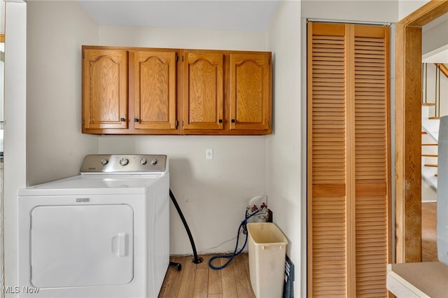 laundry area with light hardwood / wood-style floors, washer / clothes dryer, and cabinets