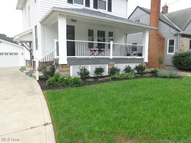 view of front of house with covered porch, a front yard, an outbuilding, and a garage