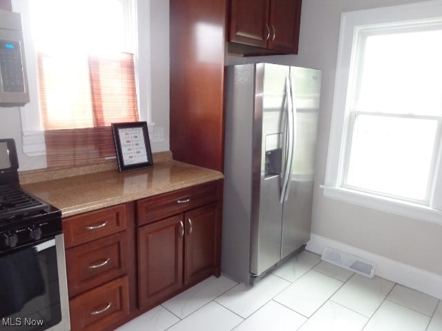 kitchen featuring light stone counters, light tile patterned flooring, and appliances with stainless steel finishes