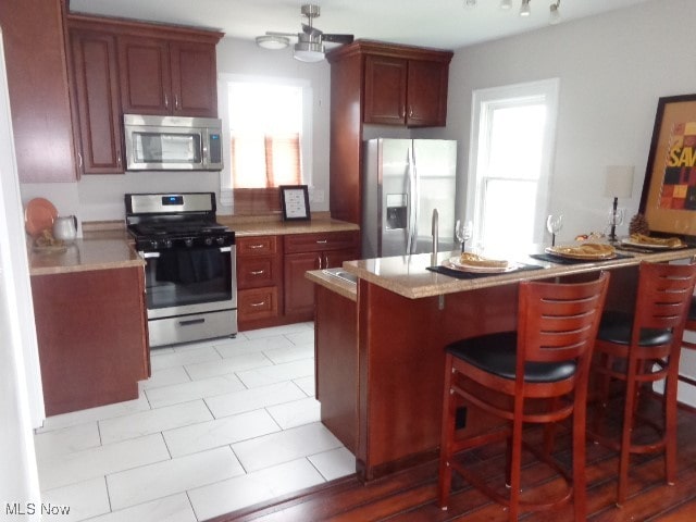 kitchen featuring stainless steel appliances, light tile patterned floors, and a kitchen breakfast bar