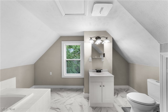 bathroom with vanity, a textured ceiling, lofted ceiling, a tub, and toilet