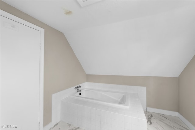 bathroom with lofted ceiling and a relaxing tiled tub