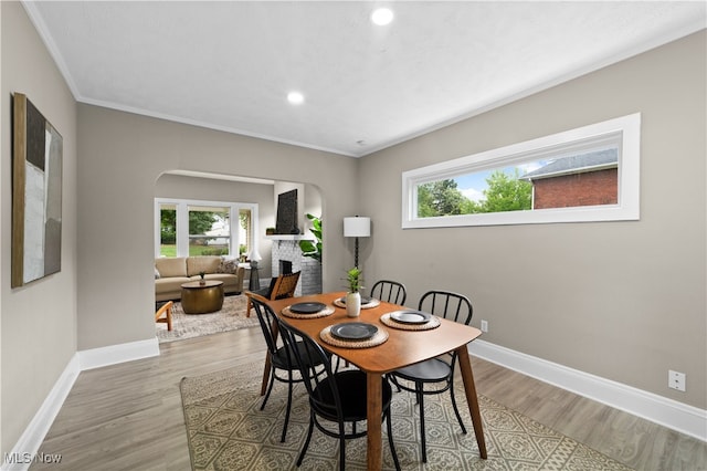 dining area with crown molding, a large fireplace, and light hardwood / wood-style flooring