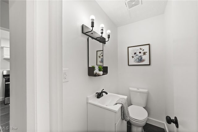 bathroom featuring vanity, tile patterned flooring, toilet, and a textured ceiling