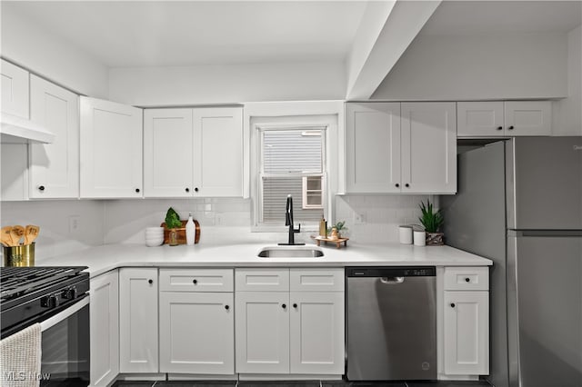 kitchen with appliances with stainless steel finishes, backsplash, sink, and white cabinetry