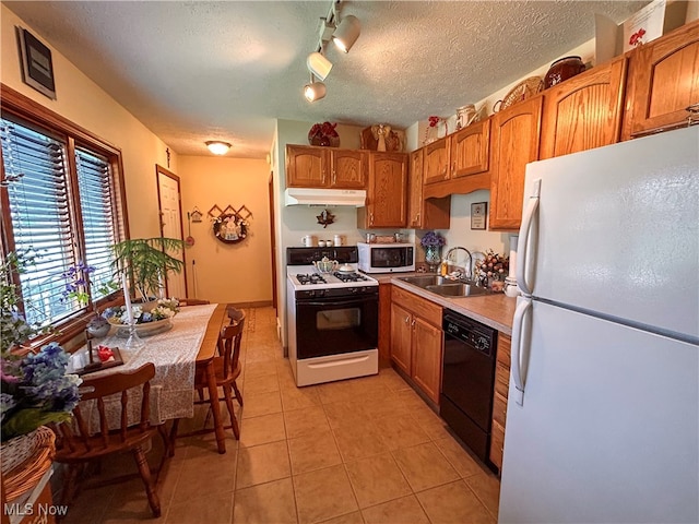 kitchen with sink, a textured ceiling, white appliances, and light tile patterned floors