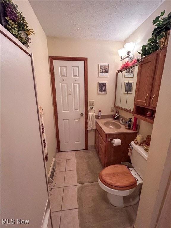 bathroom featuring vanity, a textured ceiling, toilet, and tile patterned flooring