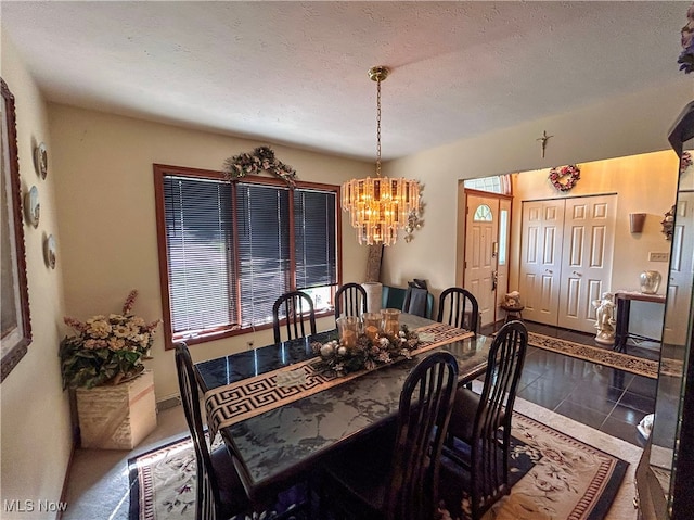 dining room featuring a chandelier, a textured ceiling, and tile patterned flooring