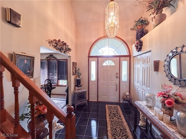 foyer with a chandelier, a high ceiling, and dark tile patterned flooring