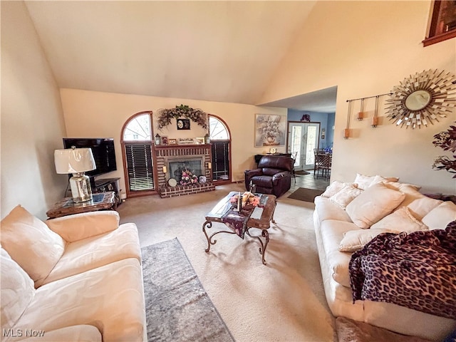 carpeted living room featuring french doors, a fireplace, and high vaulted ceiling