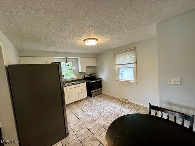 kitchen with sink, light tile patterned floors, a textured ceiling, white cabinetry, and appliances with stainless steel finishes