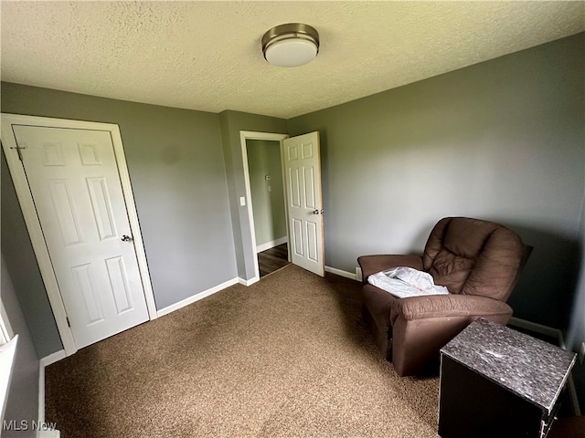 sitting room featuring dark colored carpet and a textured ceiling