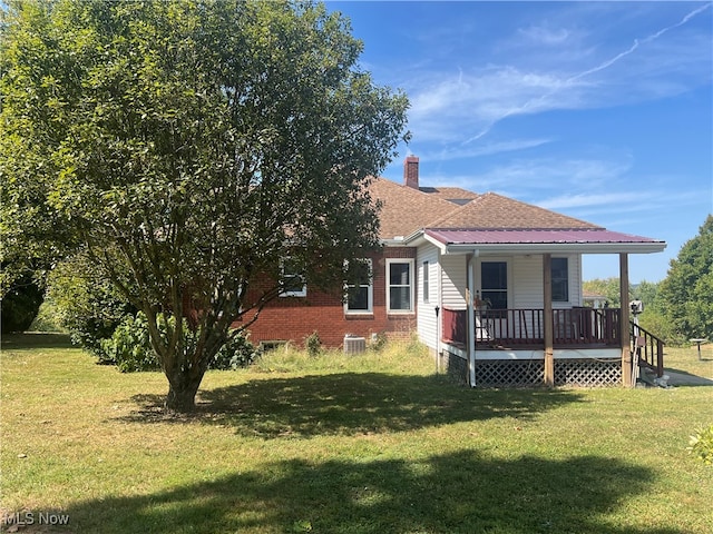 rear view of house with central air condition unit, a yard, and covered porch