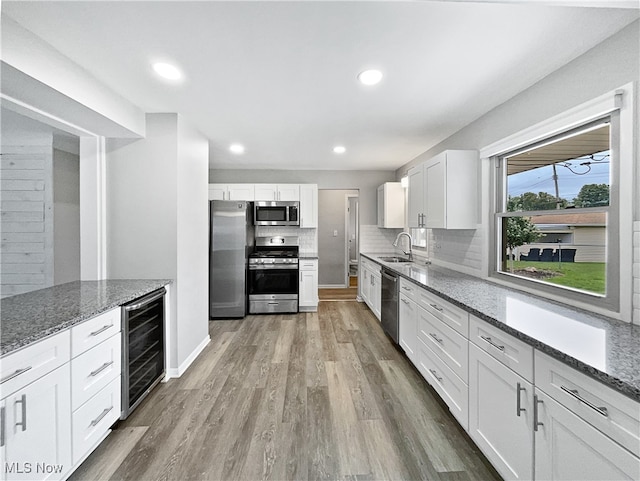 kitchen with white cabinetry, beverage cooler, sink, and stainless steel appliances