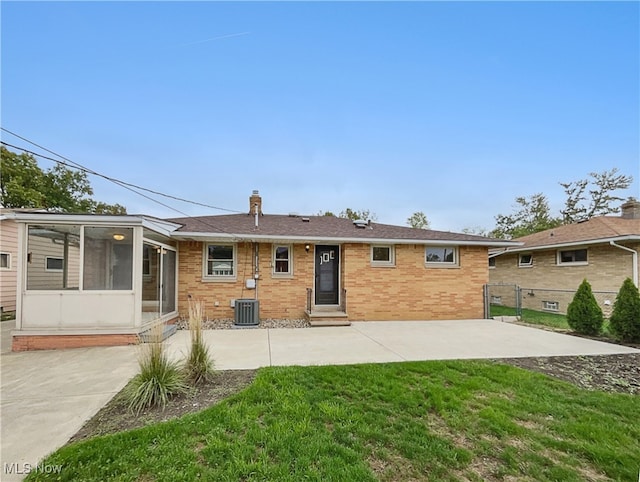 back of property with a sunroom, central AC, a patio area, and a yard