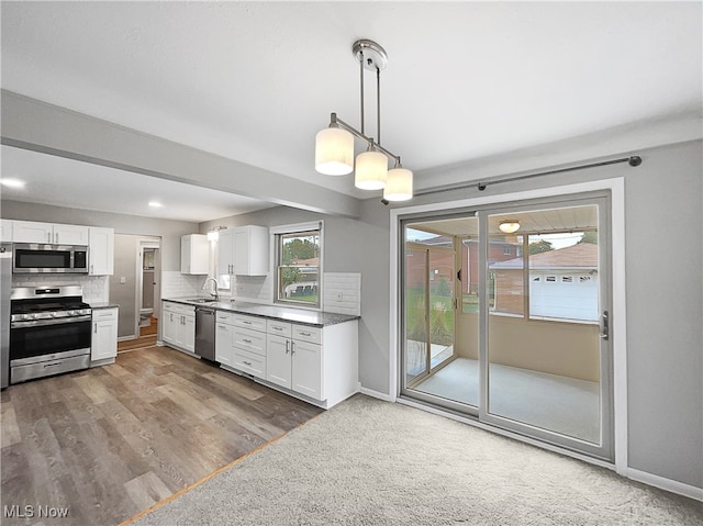 kitchen featuring stainless steel appliances, white cabinets, hanging light fixtures, and hardwood / wood-style floors