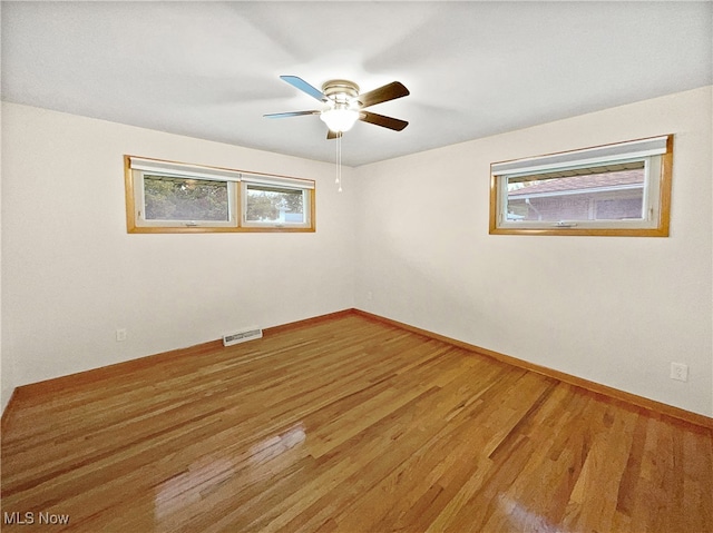 unfurnished room featuring wood-type flooring, ceiling fan, and plenty of natural light