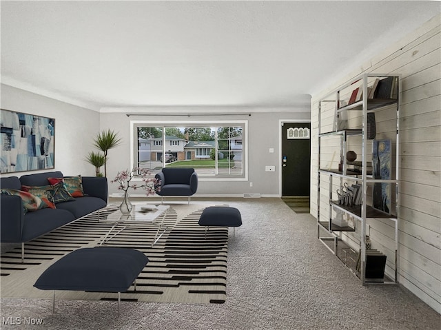 carpeted living room with wood walls