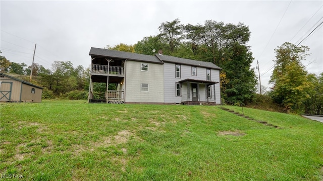 rear view of house with a shed, a balcony, and a yard