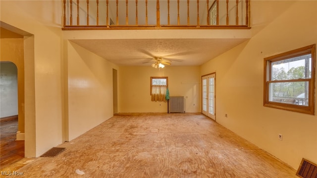 empty room with ceiling fan, radiator, and a textured ceiling