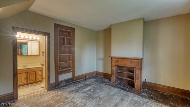 bedroom featuring lofted ceiling, sink, ensuite bathroom, and hardwood / wood-style flooring