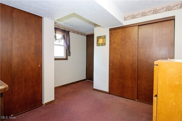 unfurnished bedroom featuring dark carpet, a closet, and a textured ceiling