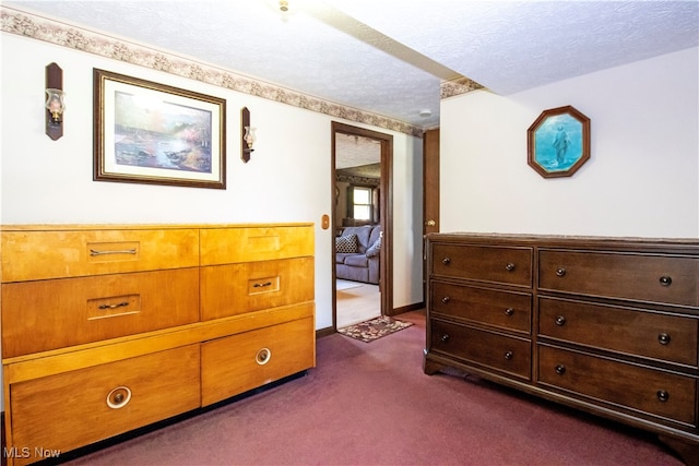 bedroom with a textured ceiling and dark colored carpet