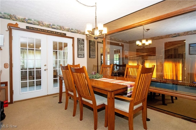 carpeted dining room featuring a chandelier and french doors