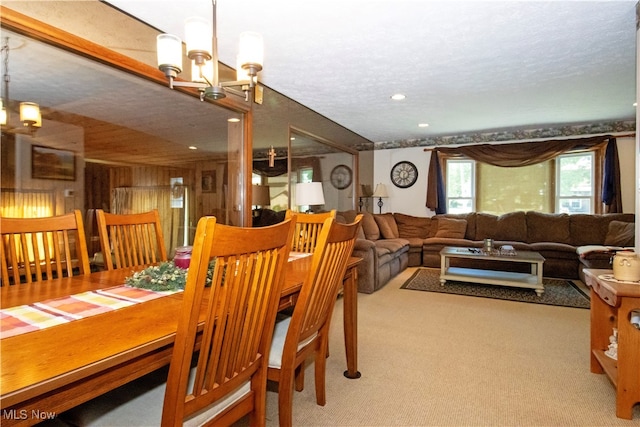 dining area featuring a textured ceiling, light carpet, and a chandelier