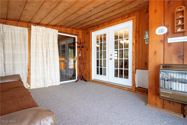 interior space featuring french doors, heating unit, wooden walls, wooden ceiling, and carpet floors