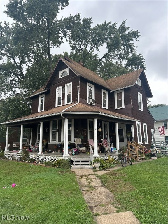 farmhouse featuring cooling unit, a front lawn, and covered porch