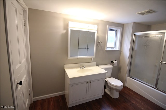 full bathroom with wood-type flooring, bath / shower combo with glass door, vanity, and toilet