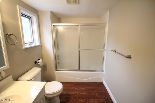 full bathroom featuring wood-type flooring, vanity, combined bath / shower with glass door, and toilet