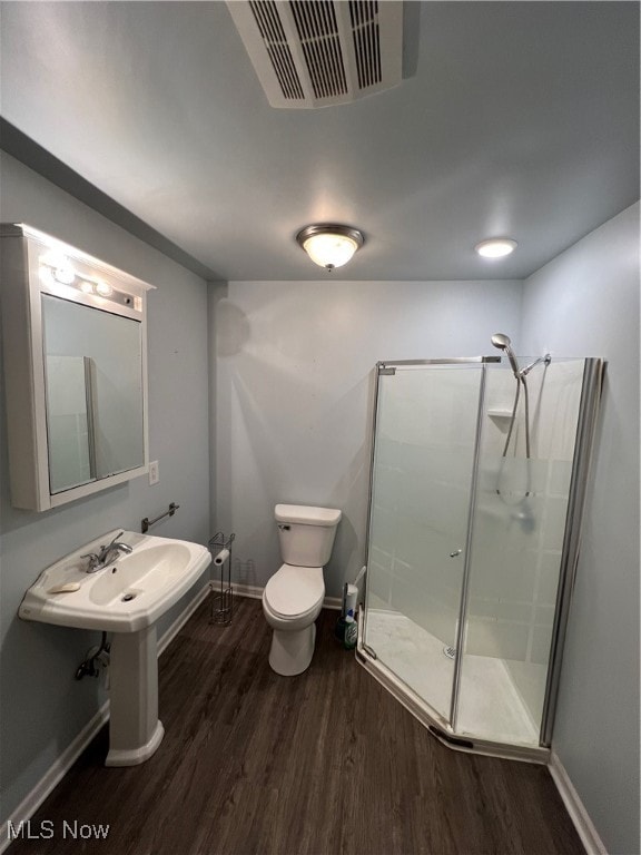 bathroom featuring wood-type flooring, an enclosed shower, and toilet